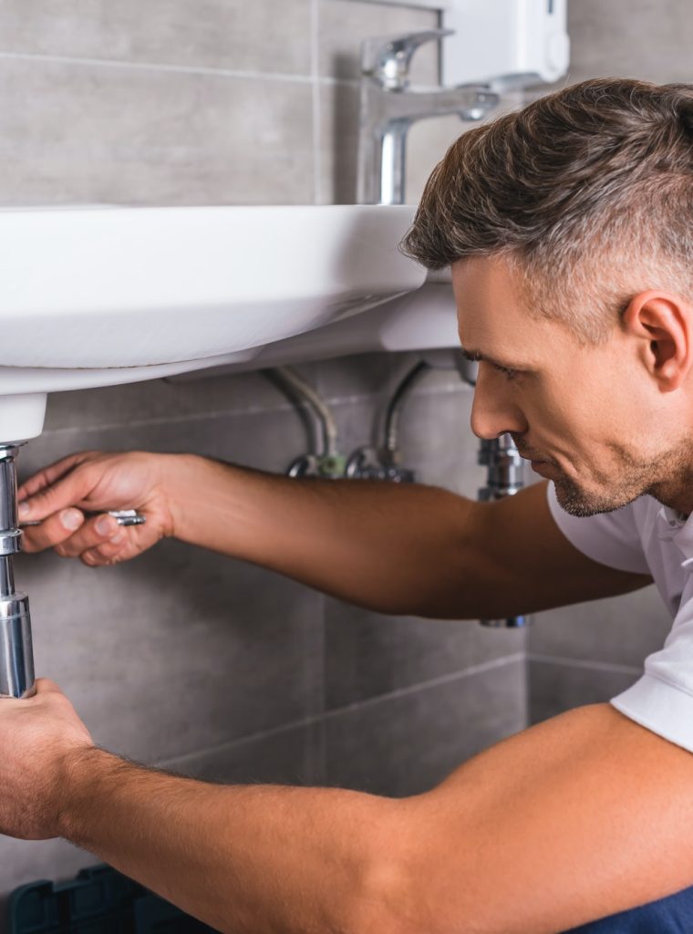 adult plumber fixing sink at bathroom